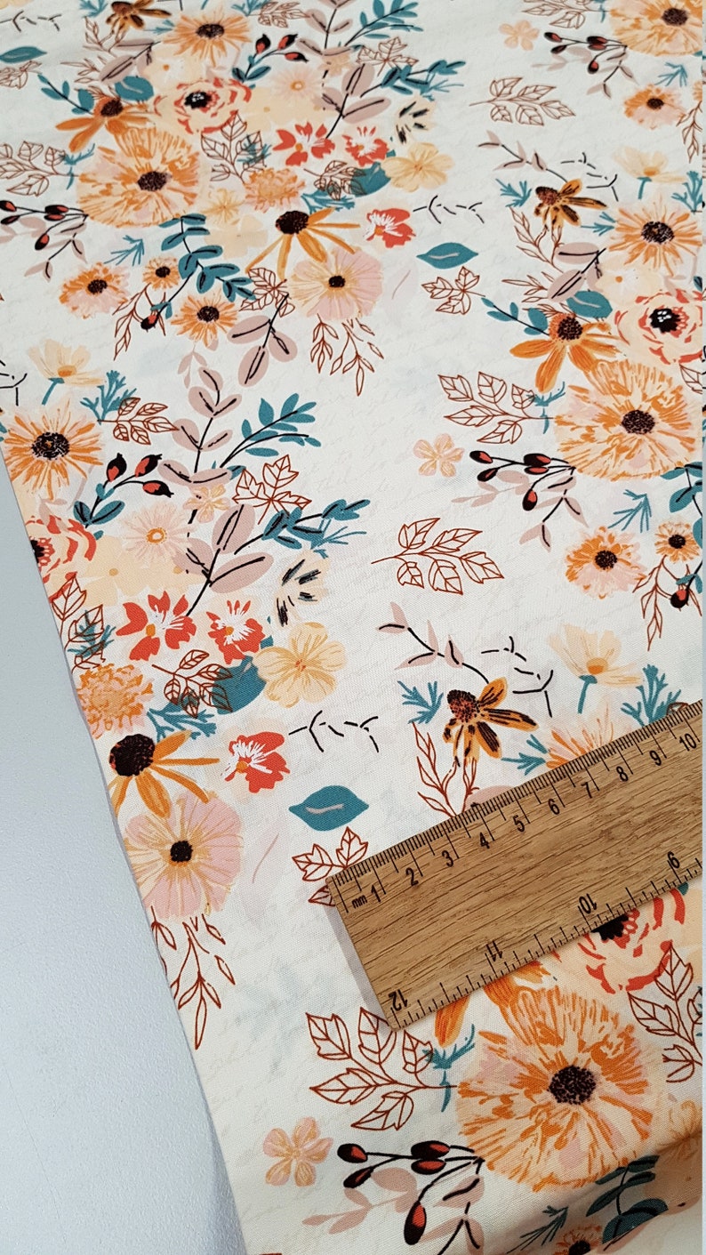 May include: White fabric with a floral print featuring orange, pink, and teal flowers. The fabric is shown with a ruler measuring 10 cm.