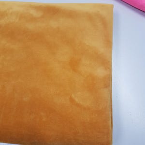 K&ouml;nnte beinhalten: Ein St&uuml;ck weicher, goldgelber Samtstoff. Der Stoff hat einen dezenten Glanz und eine glatte Textur.
