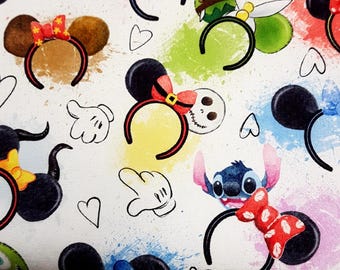 Puede incluir: Tela blanca con un estampado de diademas de personajes de dibujos animados, incluyendo Mickey y Minnie Mouse, con orejas negras, lazos y detalles de personajes. El diseño incluye salpicaduras de pintura coloridas y formas de corazón.