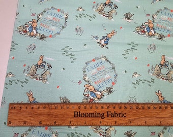 May include: A light blue fabric with a repeating pattern of Peter Rabbit holding a watering can and the text "Eating too much lettuce makes me sleepy".