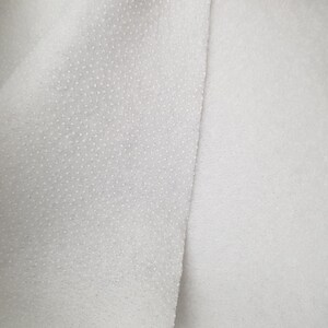K&ouml;nnte beinhalten: Nahaufnahme eines wei&szlig;en, strukturierten Stoffes mit einem glatten, wei&szlig;en Stoff daneben.