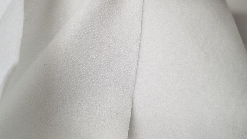 K&ouml;nnte beinhalten: Nahaufnahme eines wei&szlig;en, strukturierten Stoffes mit einem glatten, wei&szlig;en Stoff daneben.