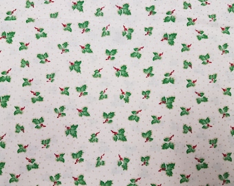 May include: White fabric with a repeating pattern of green holly leaves with red berries. The background is a light cream color.