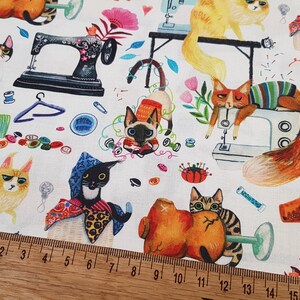 Puede incluir: Tela blanca con un patr&oacute;n repetido de gatos, m&aacute;quinas de coser y otros art&iacute;culos relacionados con la costura. Los gatos est&aacute;n en varias poses y colores, incluyendo naranja, blanco, negro y marr&oacute;n. Las m&aacute;quinas de coser son de diferentes colores y estilos. La tela est&aacute; decorada con flores, hojas y otros detalles.