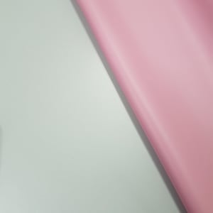 May include: A close-up of a light pink fabric surface against a light blue background.