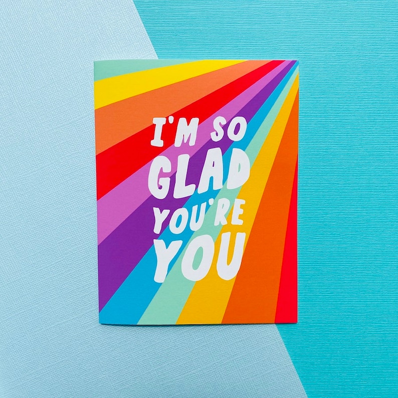 May include: A rainbow-colored card with the text "I'm so glad you're you" in white letters.