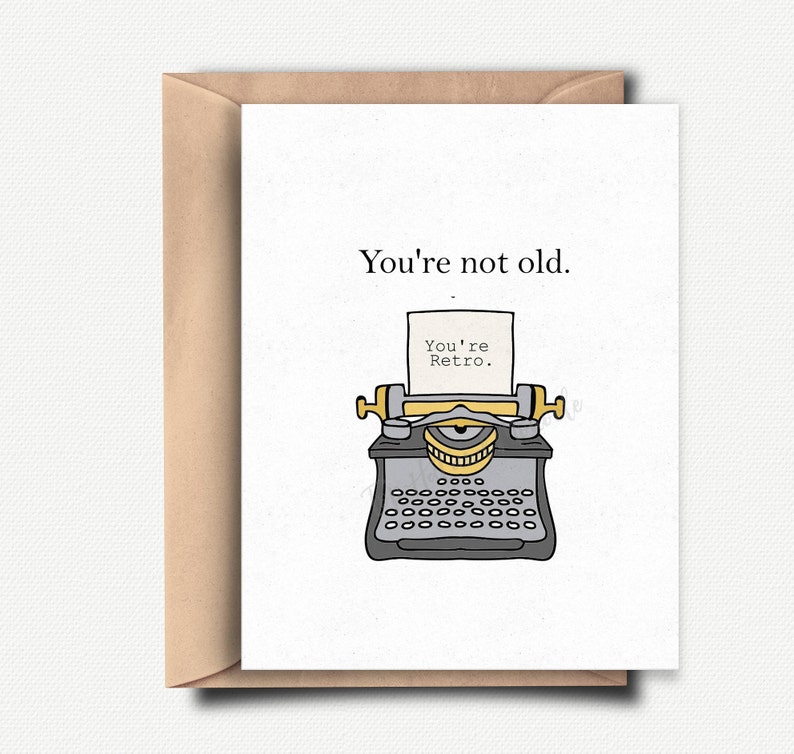 May include: A white card with a black and gray typewriter illustration. The card reads "You're not old. You're Retro."