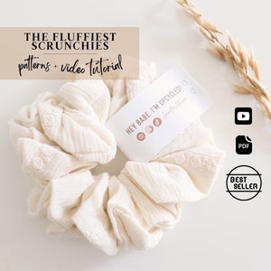 May include: A cream-coloured scrunchie made from textured fabric, with the text "THE FLUFFIEST SCRUNCHIES patterns + video tutorial". A tag reads "HEY BABE, I'M UPCYCLED!". Includes a "BEST SELLER" badge and icons for a video and PDF.