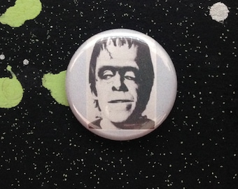 Peut inclure: Un bouton noir et blanc représentant un portrait rapproché de la créature de Frankenstein.