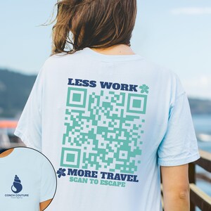May include: Light blue t-shirt with a large QR code design in teal and the text "LESS WORK" and "MORE TRAVEL SCAN TO ESCAPE" in navy blue. The shirt also features a Conch Couture logo.