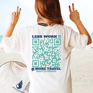 May include: White t-shirt with the text "LESS WORK" and "MORE TRAVEL SCAN TO ESCAPE" in blue. A large turquoise QR code is printed on the back. The shirt also features a small logo of a seashell and the text "CONCH COUTURE TRAVEL AGENCY".