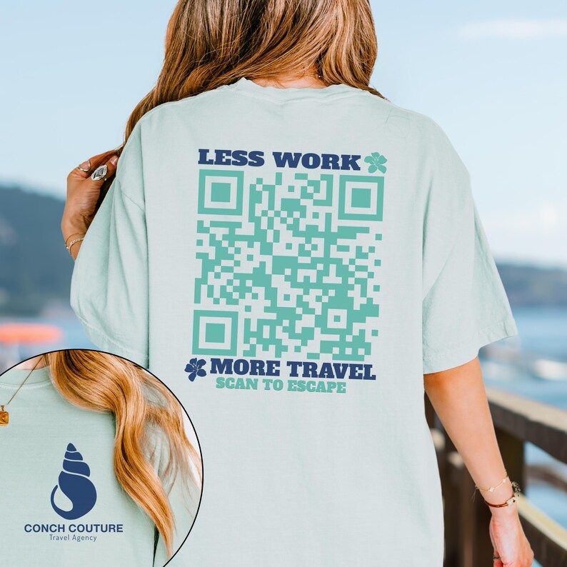 May include: A light blue t-shirt with a large QR code design in shades of teal and the text "LESS WORK" and "MORE TRAVEL SCAN TO ESCAPE". The shirt also features a Conch Couture Travel Agency logo.