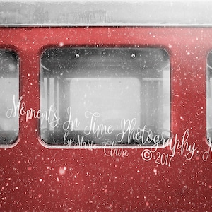 May include: A red train car with windows covered in snow. The text "Moments In Time Photography by Marie Claire © 2017" is visible on the side of the car.