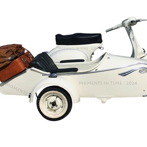 May include: A vintage white scooter with a sidecar, both with black seats. The scooter has a black handlebar and a chrome headlight. The sidecar has two brown suitcases strapped to the back. The sidecar has the text "Moments in Time 2024" printed on the side.