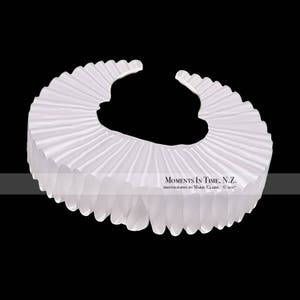 May include: A white ruffled collar, a type of costume accessory often worn for historical reenactments or theatrical performances.