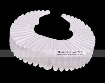 May include: A white ruffled collar, a type of costume accessory often worn for historical reenactments or theatrical performances.
