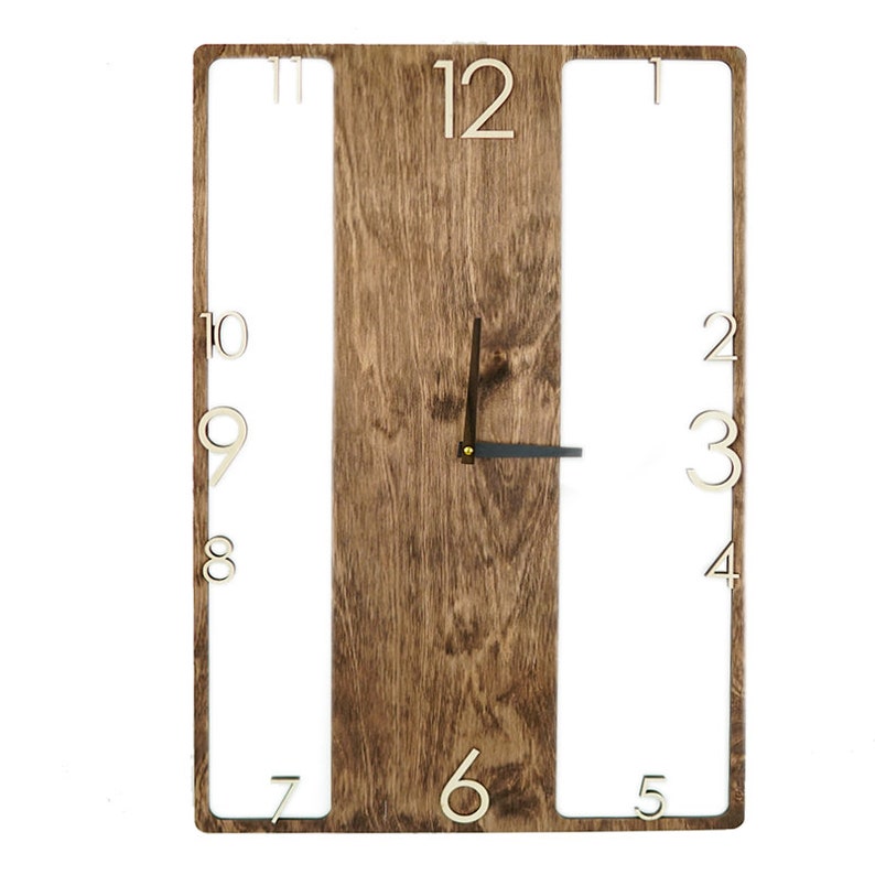 May include: A wooden wall clock with a brown wood grain finish. The clock face is surrounded by a white frame with cut-out numbers. The numbers are in a white font and are arranged in a circle around the clock face. The clock hands are black.