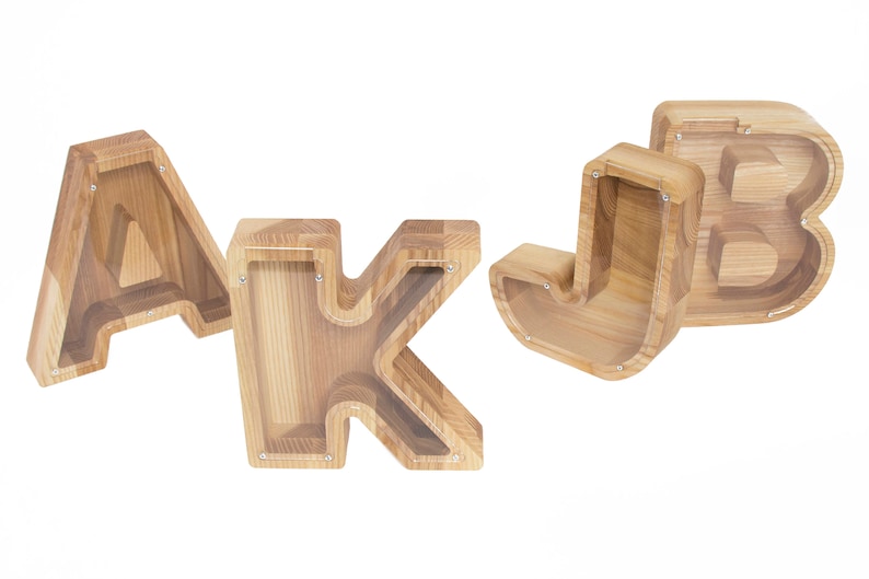 Pu&ograve; includere: Quattro salvadanai di legno a forma delle lettere A, J, K e B. I salvadanai sono realizzati in legno marrone chiaro e hanno un inserto in plastica trasparente nella parte anteriore.