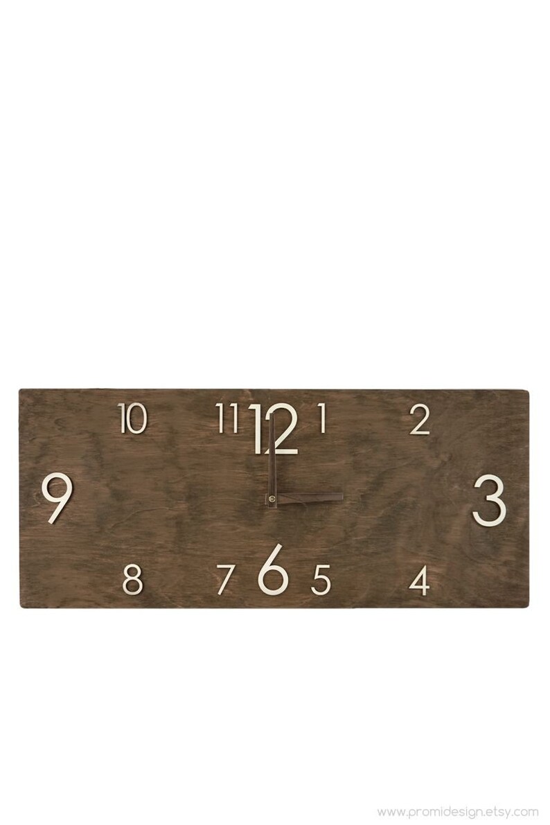 K&ouml;nnte beinhalten: Eine braune Holzuhr mit wei&szlig;en Zahlen. Das Zifferblatt der Uhr ist rechteckig und die Zahlen sind in einem Kreis um die Mitte angeordnet. Die Zeiger der Uhr sind aus Metall und zeigen die Zeit an.