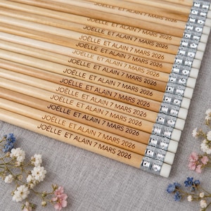 May include: A collection of light-colored wooden pencils arranged in a parallel row. Each pencil features a silver metal ferrule with a white eraser and is engraved with the text JOËLLE ET ALAIN 7 MARS 2026 in a dark, clear, sans-serif font.