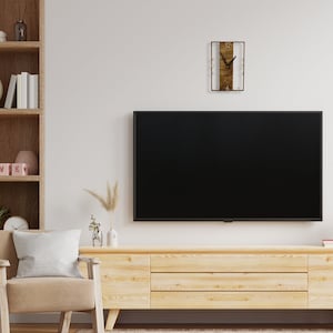 May include: A wooden wall clock with a white background and black hands. The clock is hanging on a white wall above a black television and a wooden entertainment center.