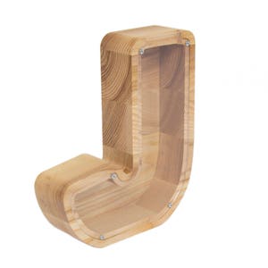 Pu&ograve; includere: Salvadanaio di legno a forma della lettera J. Il salvadanaio &egrave; realizzato in legno naturale con un fronte in plastica trasparente per vedere le monete all'interno.