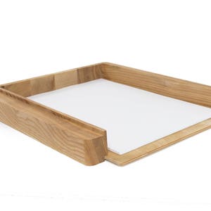 Può includere: Un organizzatore da scrivania in legno con un vassoio estraibile. L'organizzatore è realizzato in legno marrone chiaro e ha una finitura naturale.