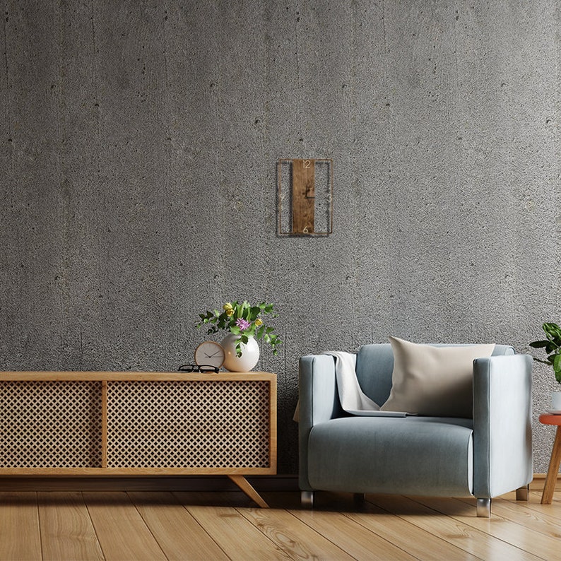 May include: A light blue armchair with a beige pillow sits in front of a concrete wall. A wooden shelf with a clock hangs on the wall. A wooden cabinet with a lattice design sits in front of the chair. A vase with flowers sits on top of the cabinet.