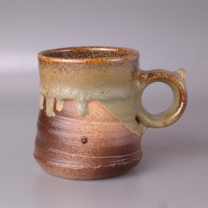 Op de afbeelding: Een bruine en beige keramische mok met een druppelglazuur. De mok heeft een rond lichaam en een handvat.