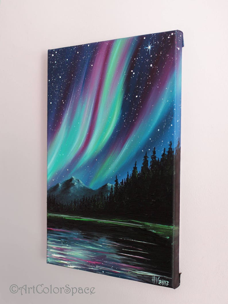 May include: A painting of the aurora borealis over a lake and forest. The sky is a deep blue with streaks of green, purple, and pink light. The trees are silhouetted against the sky, and the lake is reflecting the light of the aurora. The painting is signed "HV 2017" in the lower right corner.