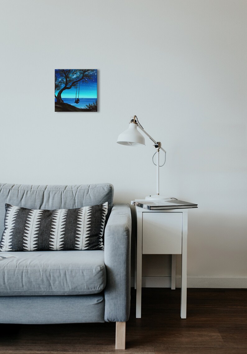 Pode incluir: Uma pintura de uma &aacute;rvore com um balan&ccedil;o pendurado em seus galhos. A &aacute;rvore est&aacute; silhuetada contra um c&eacute;u azul com estrelas. O oceano &eacute; vis&iacute;vel no fundo.