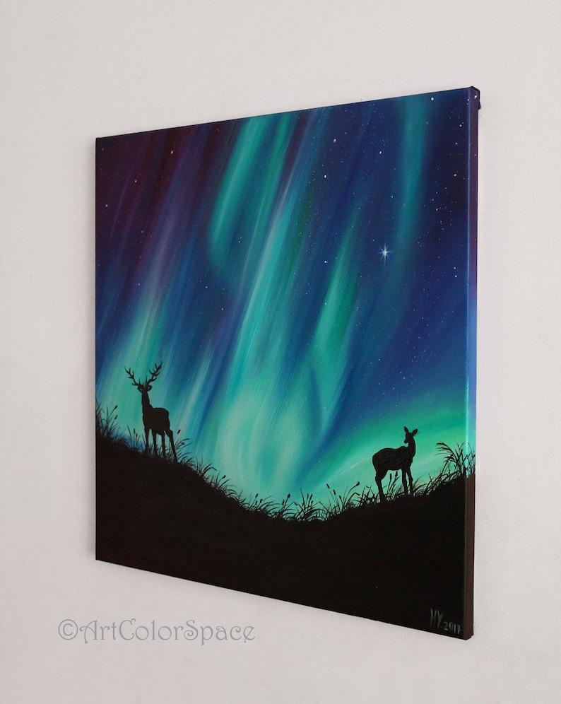 May include: A painting of a starry night sky with a vibrant green and blue aurora borealis. Two deer silhouettes stand in the foreground, one with antlers, against a dark landscape.