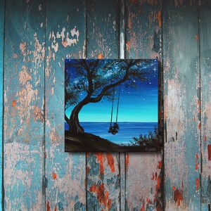 Pode incluir: Uma pintura que retrata uma silhueta de uma pessoa em um balan&ccedil;o sob uma &aacute;rvore, com um c&eacute;u noturno estrelado e um mar azul escuro no fundo.