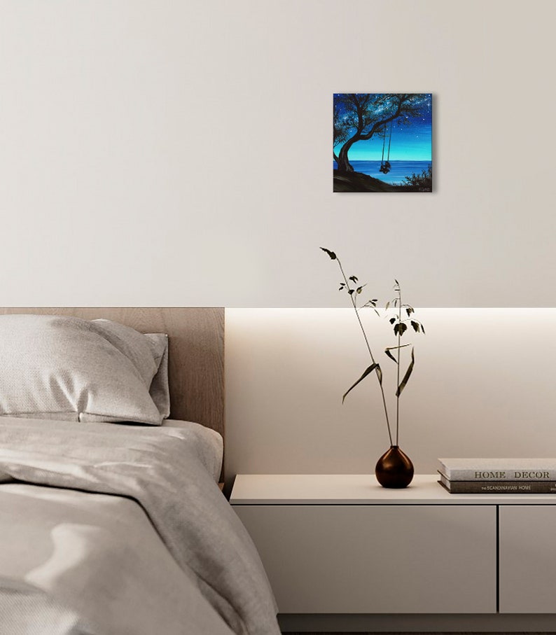 Pode incluir: Uma pintura que representa a silhueta de uma &aacute;rvore com um balan&ccedil;o pendurado em um galho. A &aacute;rvore est&aacute; situada em um penhasco com vista para um corpo de &aacute;gua. O c&eacute;u &eacute; azul escuro com estrelas.