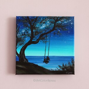 Pode incluir: Uma pintura que retrata a silhueta de uma pessoa sentada em um balan&ccedil;o sob uma &aacute;rvore, com um c&eacute;u noturno estrelado e um oceano azul ao fundo.