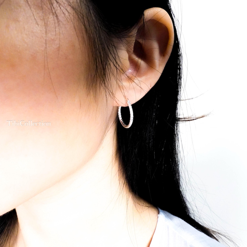 Model wearing thin sterling silver hoop earrings close up