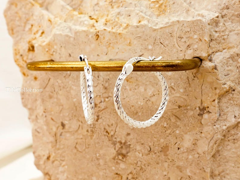 Sterling silver textured hoops catching light and shine