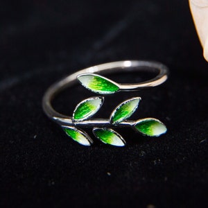 Pode incluir: Um anel de prata com um design de folhas verdes. As folhas s&atilde;o esmaltadas em tons de verde e branco.