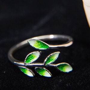 Pode incluir: Um anel de prata com um delicado design de ramo com folhas de esmalte verde. O anel &eacute; ajust&aacute;vel e de extremidade aberta.