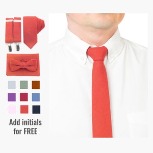 Puede incluir: Conjunto de corbata, pajarita, tirantes y pañuelo de bolsillo de color coral. La corbata está anudada alrededor de una camisa blanca con cuello. Se muestran muestras de color debajo de los accesorios. Texto: Añade iniciales GRATIS.