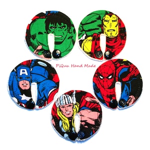 May include: Five round fabric patches featuring different superheroes from Marvel Comics. The patches are white with a black border and feature images of Hulk, Iron Man, Captain America, Spiderman, and Thor. The text "Piquu Hand Made" is printed in pink on the white background.