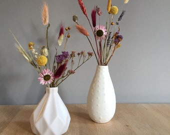 Set van twee witte vazen van verschillende hoogtes met droogbloemen