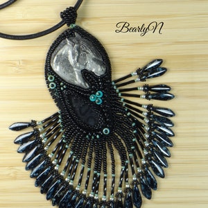 May include: A black beaded necklace with a silver horse head pendant. The horse head is surrounded by black beads and turquoise accents. The necklace has a fringe of black and silver beads.