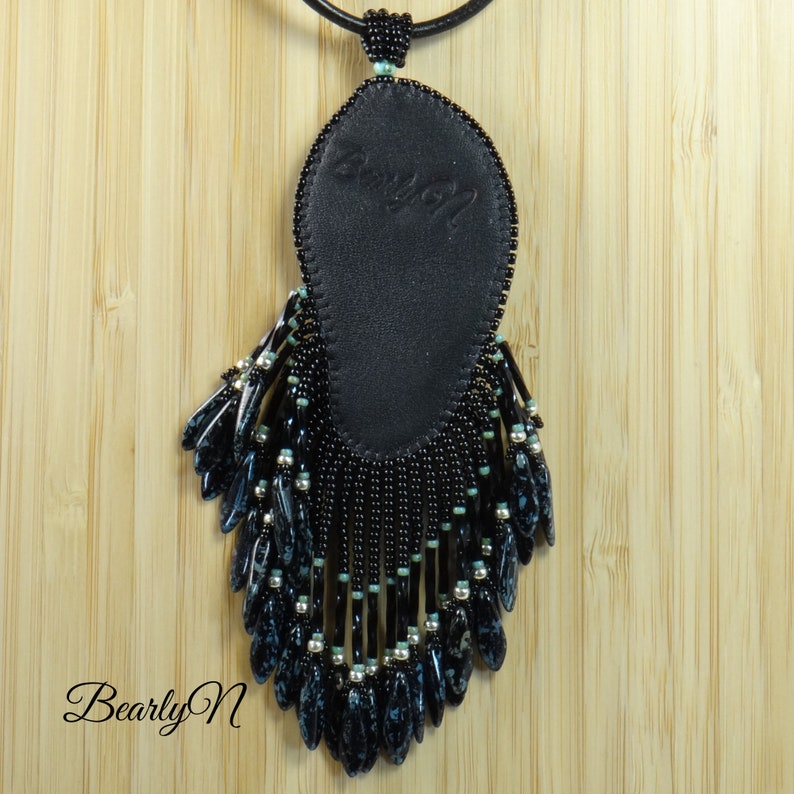 May include: Black beaded necklace with a black leather pendant and a fringe of black and blue beads.