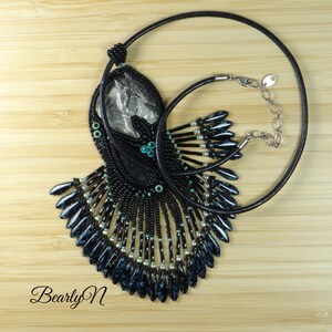 May include: A black beaded necklace with a silver horse head pendant. The necklace features a fringe of black and blue beads.