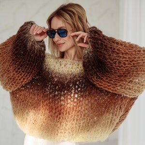 Könnte beinhalten: Ein brauner, gelber und weißer Ombre-Strickpullover mit lockerer, Oversize-Passform. Der Pullover ist aus weichem, flauschigem Garn gefertigt und hat einen lässigen, entspannten Stil.