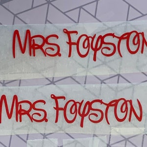 Puede incluir: Dos hojas blancas de papel con el texto "MRS FOYSTON" escrito en letras cursivas rojas.