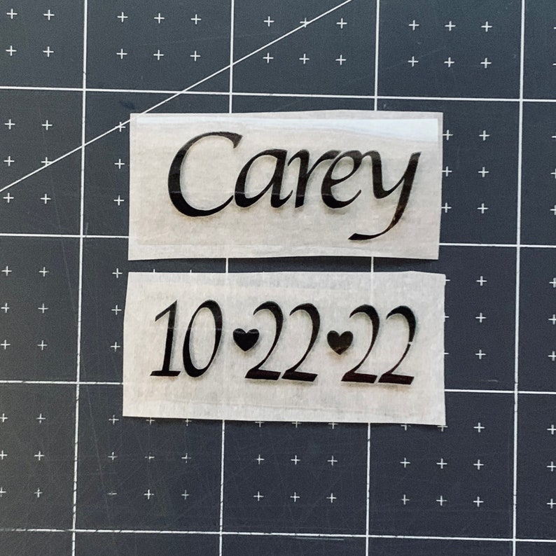 May include: Two pieces of white paper with black text. The top piece says "Carey" and the bottom piece says "10-22-22" with two small hearts between the numbers.