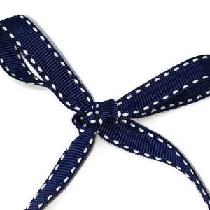 May include: A navy blue ribbon with white stitching, tied in a bow.