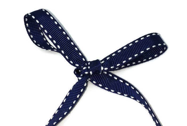May include: A navy blue ribbon with white stitching, tied in a bow.